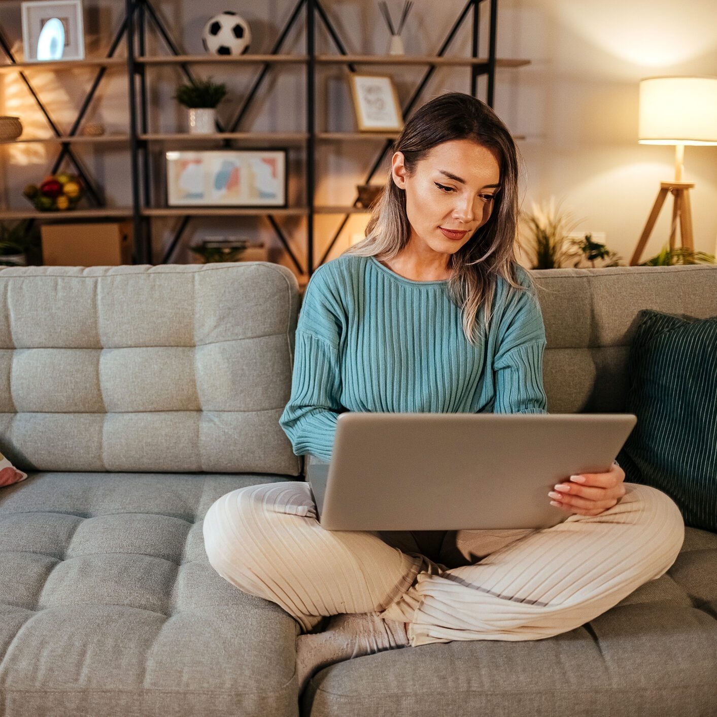 Woman sitting criss cross on a couch using a laptop